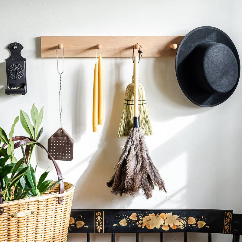 Feather duster hanging from a wall rack among other household tools.