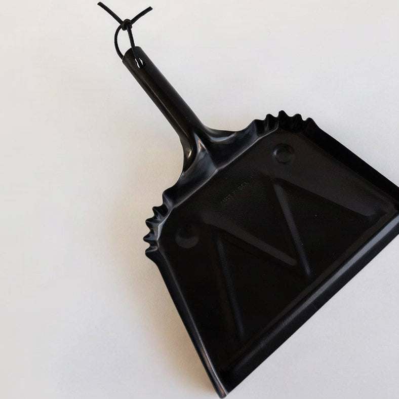 Angled view of the black steel Farmhouse Dustpan with a leather hanging loop.