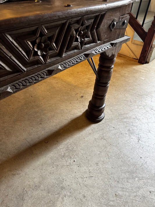 Detail of the Florian Writing Desk showing floral rosettes, geometric carved panels, dark wood and a turned leg.