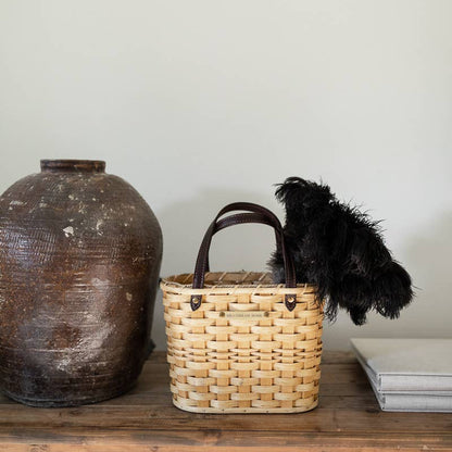 Feather duster resting across a woven basket beside a clay vessel.