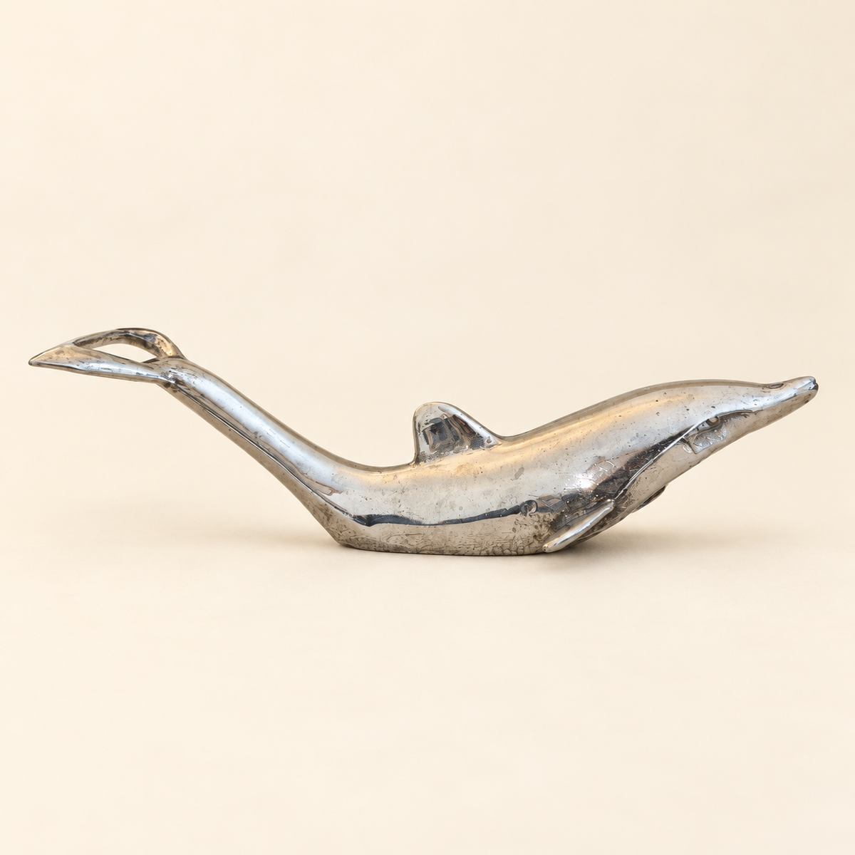 Silver-toned dolphin bottle opener with original surface patina