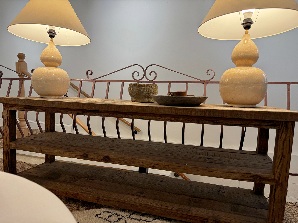 Dunham wooden console with two open shelves, styled with yellow lamps and bowls.