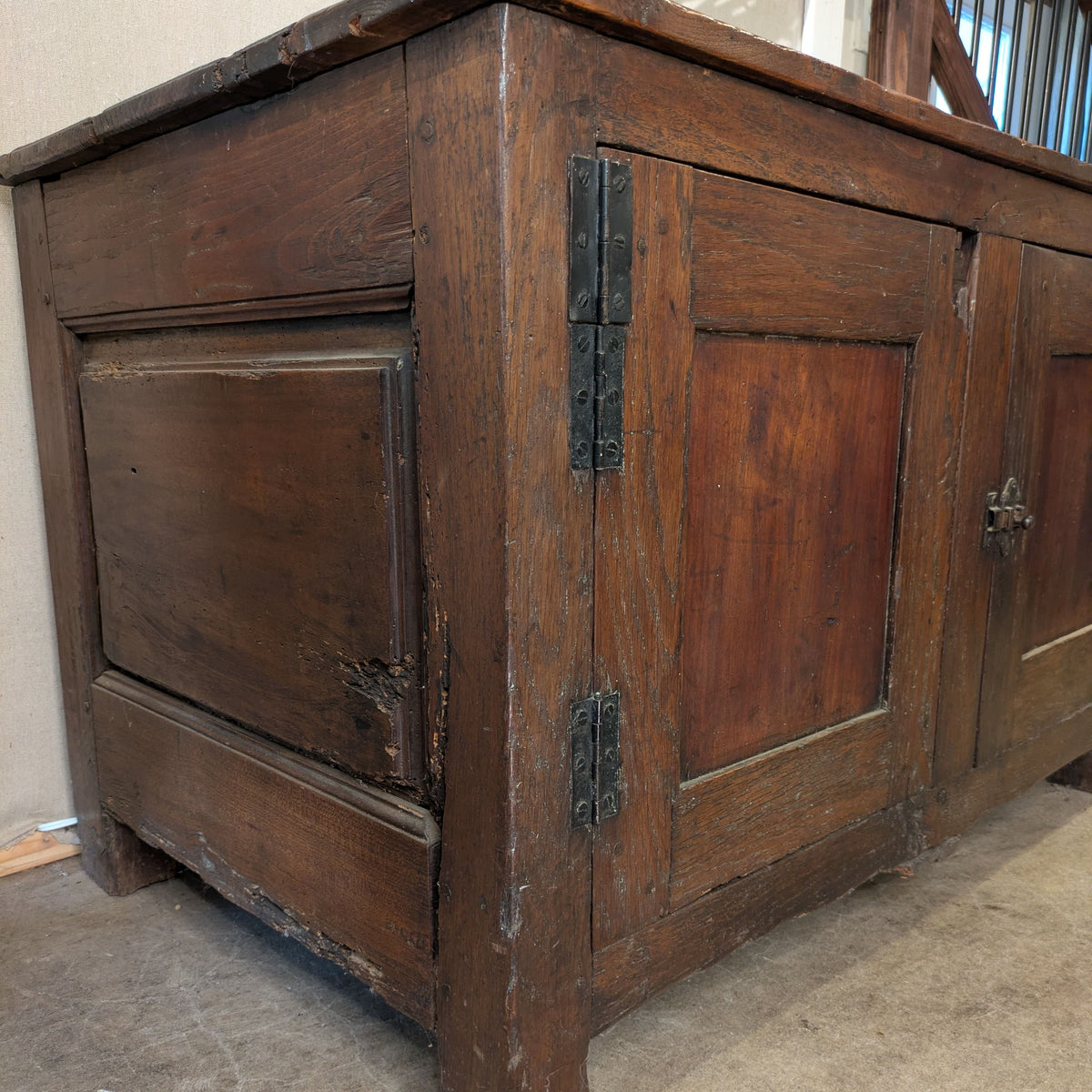Three-quarter view of Montel Low Cabinet showing its paneled side, door hinges and short feet.