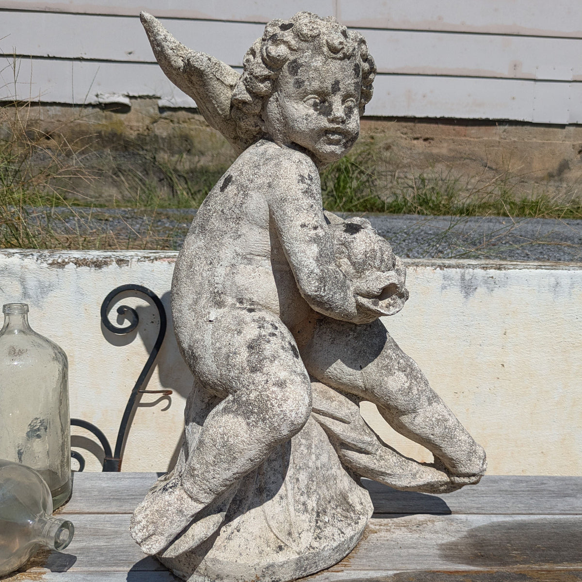 Side view of Concrete Water Sprite showing the figure's curly hair and the raised tail of the fish.