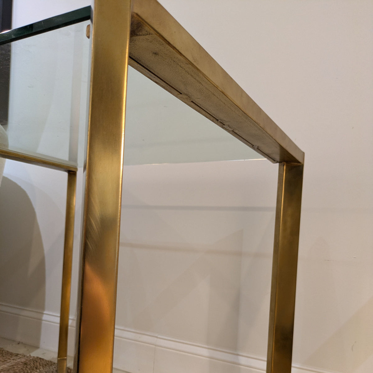 Close-up of Varenne Glass Side Table's gold-toned metal frame, upright legs and glass-top edge.