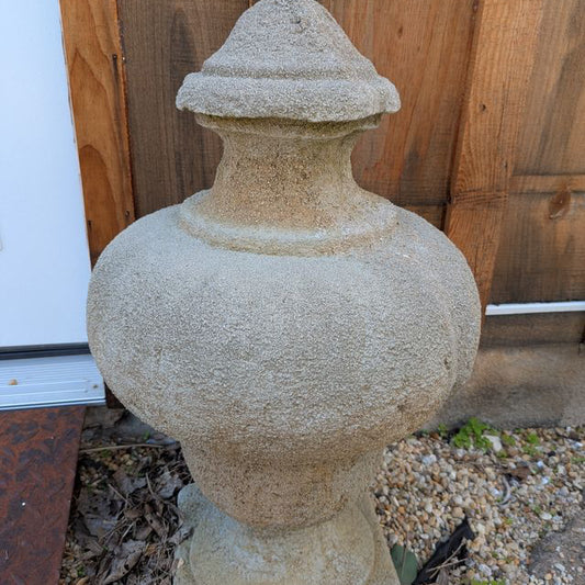 Close view of one Valmont garden finial showing its rounded body, narrow neck and textured grey surface.