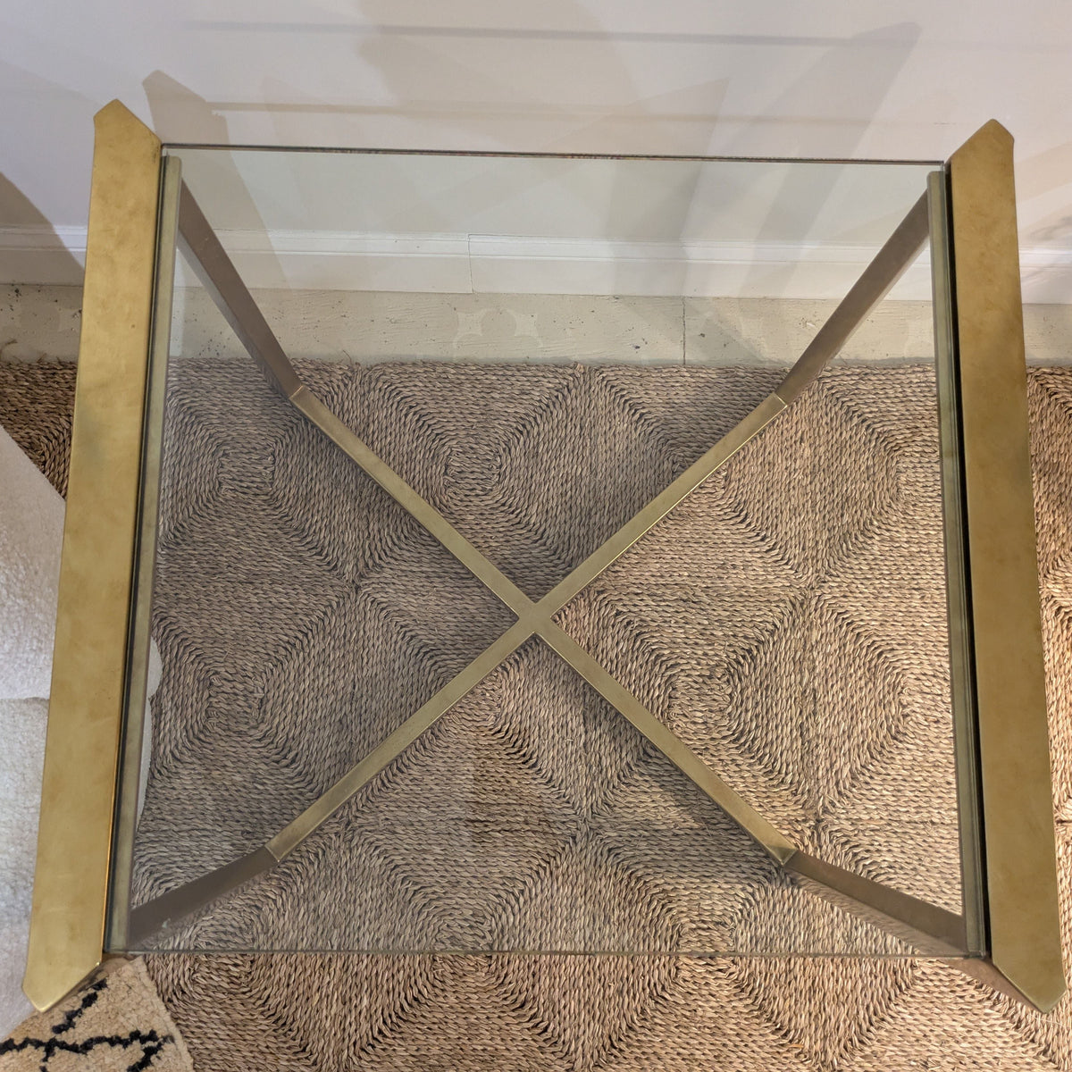 Top view of Varenne Glass Side Table showing its glass surface, two raised side rails and crossed base below.