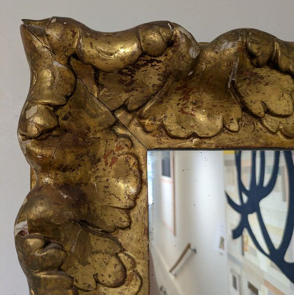 Close-up of Aurèle Wall Mirror's upper-left frame corner, showing raised leaf forms and a mottled gold-toned surface.